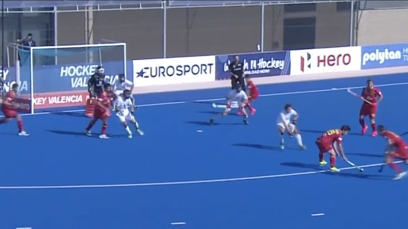 Side view of a Caucasian female field hockey player, during a field hockey  game, executing a penalty kick, with a goal protected by a goalkeeper in  the background, on a sunny day